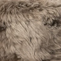 Close-up view of soft, fluffy, light brown sheepskin with various shades of tan and subtle dark streaks. The thick, plush texture suggests cosy warmth, making it a popular choice for home décor or fashion accessories.
