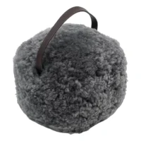 The Battleship Grey Sheepskin Door Stop is a round, fluffy, grey accent with a dark brown handle, isolated on white. Its soft texture makes it perfect as a cosy door stop or stylish decorative piece for your home.