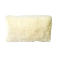 A rectangular, cream-coloured pillow with a fluffy, textured surface resembling wool is shown against a plain white background. The pillow appears soft and plush, with rounded edges and a slightly uneven surface. Sheepskin.