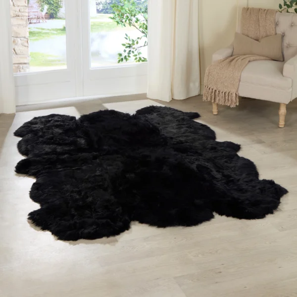 A Midnight Black 6 Pelt Sheepskin Rug with scalloped edges rests on a light wooden floor in a bright room, near French doors with white curtains and beside a beige armchair draped with a tan throw.