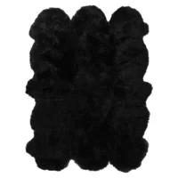 The Midnight Black 6 Pelt Sheepskin Rug is a fluffy, rectangular rug with a wavy, irregular edge and a thick, plush texture that reflects light for a subtle glossy appearance.