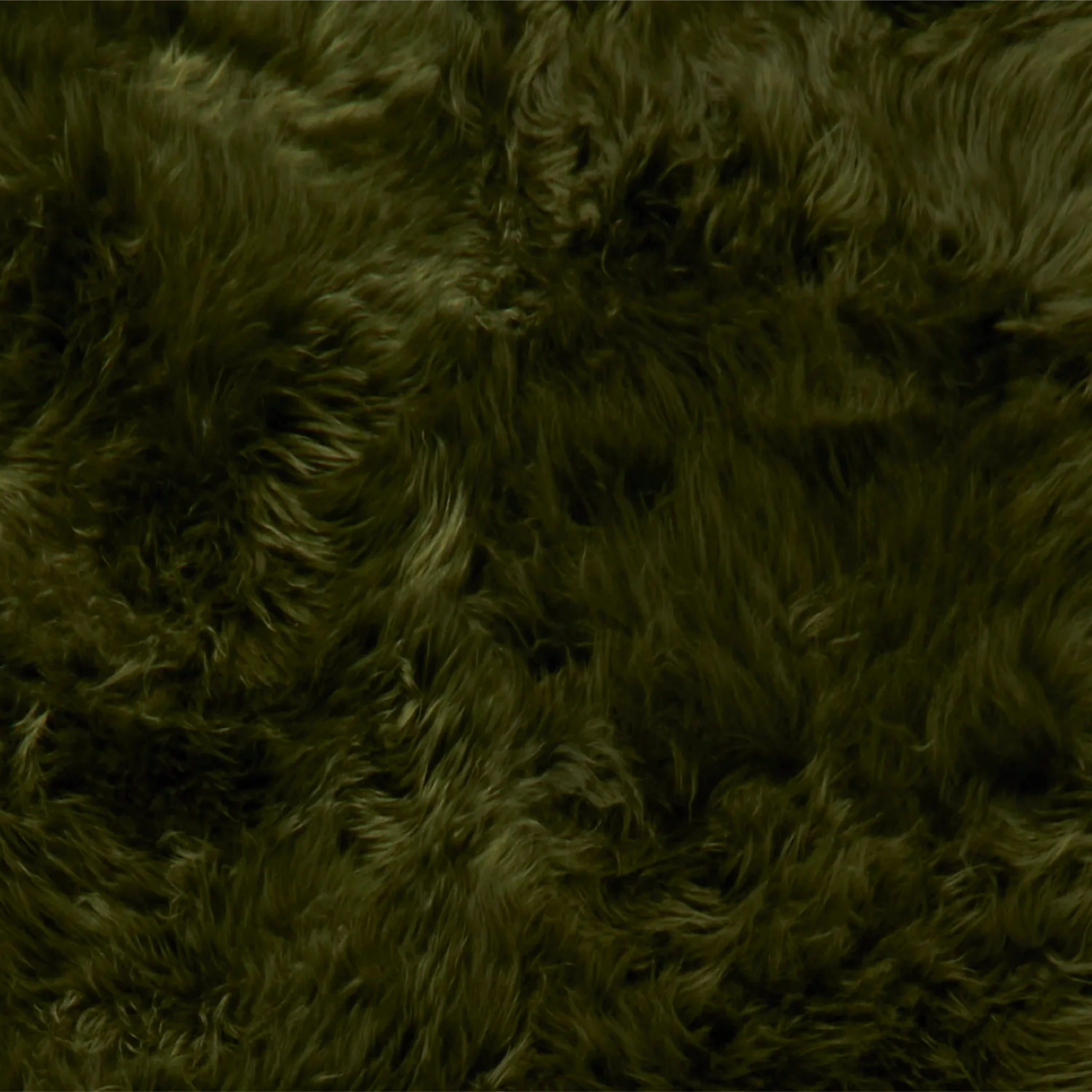 A close-up of the Green Sheepskin Rug – Extra Large reveals thick, plush dark green fur with a wavy texture. The soft, fluffy strands show subtle highlights and shadows that emphasise their natural direction and flow.